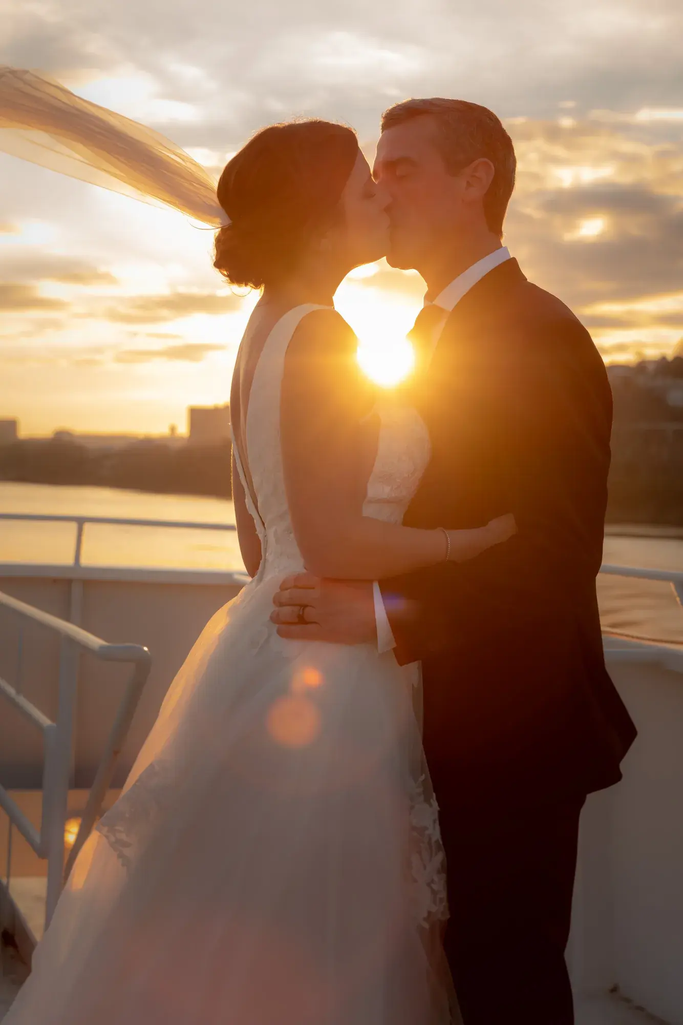 Bride and groom kissing at sunset on the deck of The Destiny yacht in Cincinnati